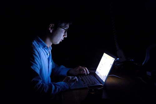 暗闇でパソコンを操作する男性